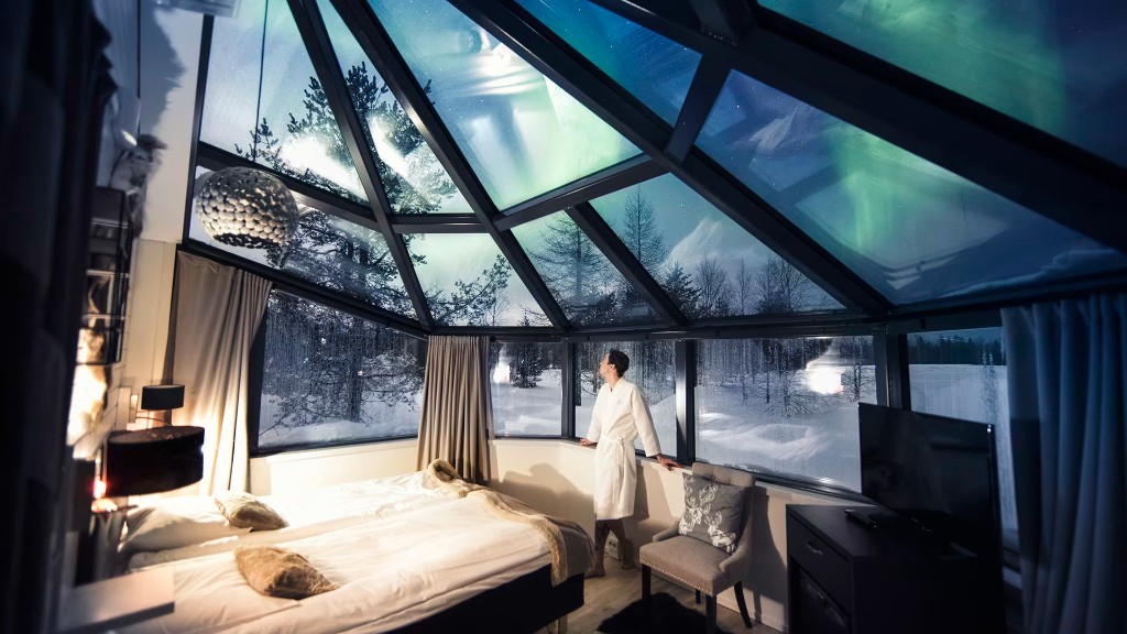 Guest enjoying a glass igloo bedroom beneath the Northern Lights
