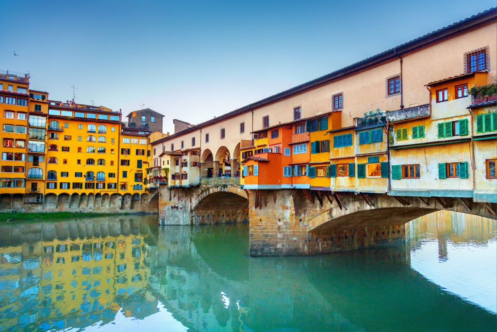 Ponte Vecchio over the Arno with colorful medieval buildings reflected in the water, Florence