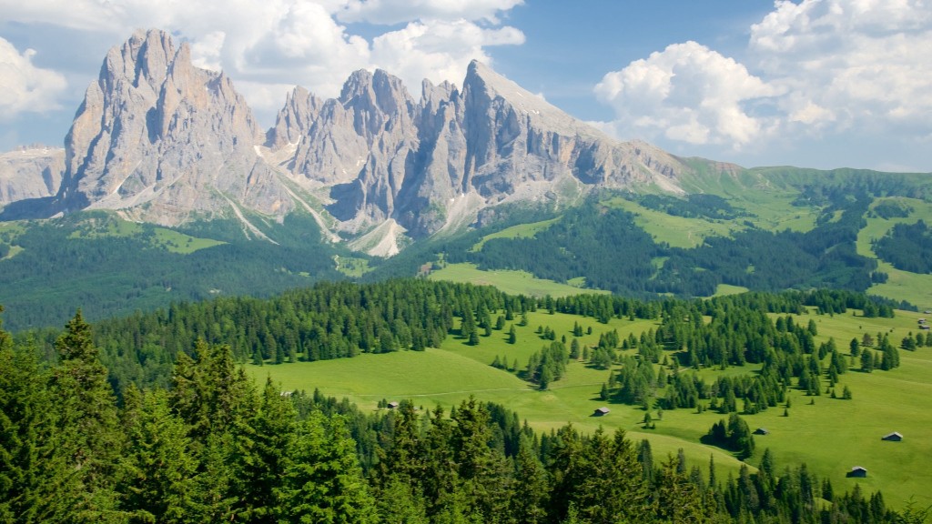 Alpe di Siusi alpine meadow with Sassolungo massif, scattered huts and forested foreground