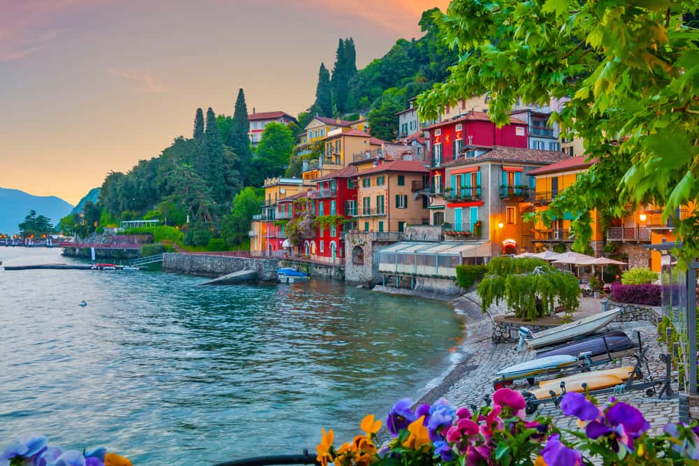 Varenna on Lake Como at golden hour: flower boxes, colourful lakeside houses, boats on deep blue water, distant mountains