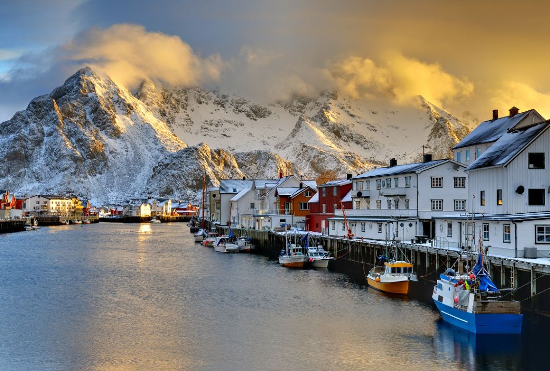 Red fishing cabins below snow-covered peaks in the Lofoten Islands