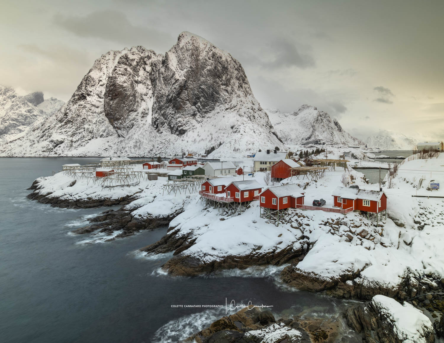 Red rorbuer cabins at Hamnøy beneath snowy Lofoten peaks